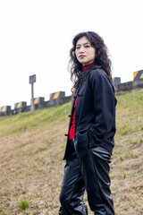 An Asian woman in a black leather coat outdoors