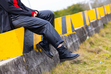 A woman dressed in black leather sat on a stone pier