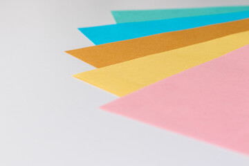 白い机に並べられた明るいパステルカラーの紙
