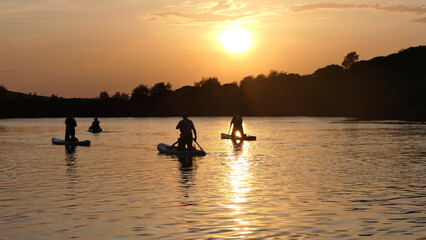 Paddleboarding on a lake on a summer evening at the golden hour into the sunlight