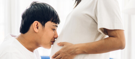 Fototapeta na wymiar Romantic sweet asian couple husband hugging and smiling beauty asian pregnant wife.Man expecting with woman pregnancy hold and kiss to baby in belly at home