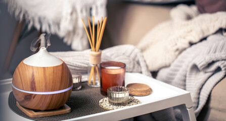 A cozy composition with an aroma diffuser and candles in a home interior. - obrazy, fototapety, plakaty