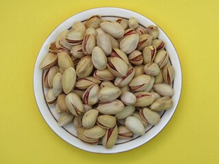 Pistachio in a plate on yellow background