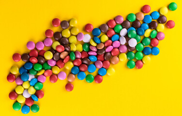 Multicolored candies on a bright yellow background.Top view