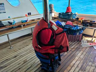 Bright life jackets are strapped to an iron pipe on a yacht. Flippers and masks are in the box...