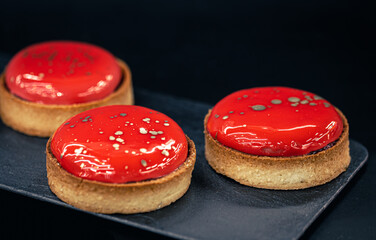 Close-up of red pastry tarts on a black background.