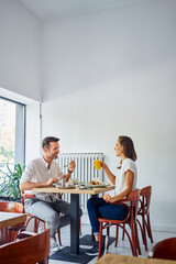 Happy couple eating breakfast at cafe. Man and woman enjoying meal in restaurant.