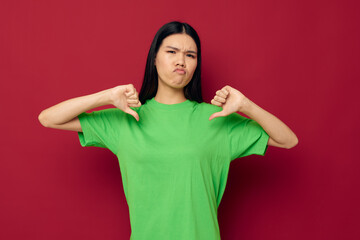 Charming young Asian woman green t-shirt gestures with his hands red background unaltered