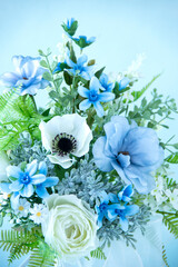 幸せを願う白と青のウェディングブーケのクローズアップ（アネモネ、バラ、ラナンキュラス、ブルースターなどの造花）