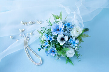 真珠のネックレスと幸せを願う白と青のウェディングブーケ（アネモネ、バラ、ラナンキュラス、ブルースターなどの造花）