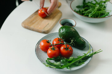 Woman preparing vegetable salad with tomato in the kitchen. Healthy food vegan salad. Mindful eating