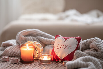 Obraz na płótnie Canvas Cozy Valentine's Day background with a candle and a decorative heart.