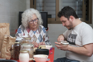 Mother and adult son making sweets together. Family cooking.