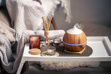 A cozy composition with an aroma diffuser and candles in a home interior.