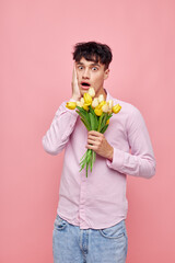pretty man in a pink shirt with a bouquet of flowers gesturing with his hands pink background unaltered