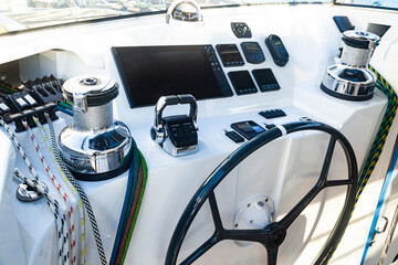 Cabin of a sailing yacht. Navigation pad with steering wheel, sailing winches with cables, shift...