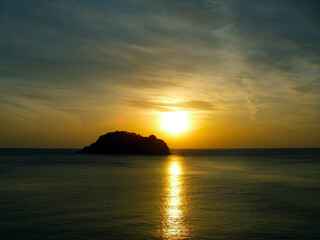 Gold shining sunset sea view with a island silhouette image photography. 西伊豆から観る海面を黄金色に照らす宇留井島に向かって落ちる夕陽。