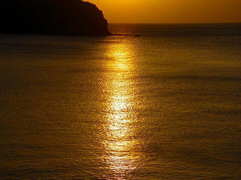 Gold shining sunset sea view with a island silhouette image photography. 西伊豆から観る海面を黄金色に照らす宇留井島に向かって落ちる夕陽。