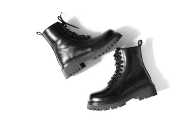 Isolated leather black boots with one stepping onto the other with shadows falling down on white...