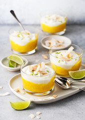 Sweet mango puree and cream cheese layered dessert decorated with roasted coconut chips and grated...