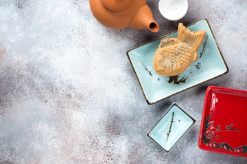 Taiyaki or japanese traditional fish-shaped cake on a turquoise plate, top view on a roseate metal background, copy space