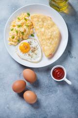White plate with chicken eggs cooked in different ways, vertical shot on a light-blue stone background, flatlay