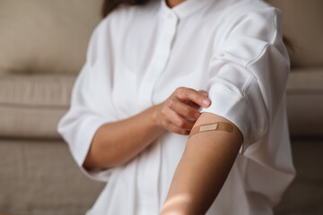 Closeup image of a woman with adhesive bandage, medical plaster, band aid on her arm