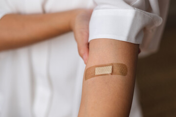 Closeup image of a woman with adhesive bandage, medical plaster, band aid on her arm