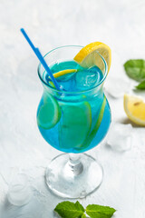blue cold drink and ice cubes, with fresh green mint leaves on deep blue and light blue background. Alcoholic or non-alcoholic cold longdrink