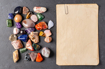 Mineral stones and an old piece of paper. Black concrete background. The concept of using minerals...