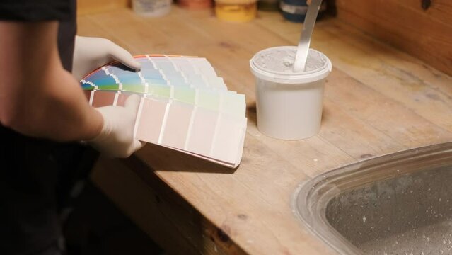 A worker examines a palette of colors to select a paint