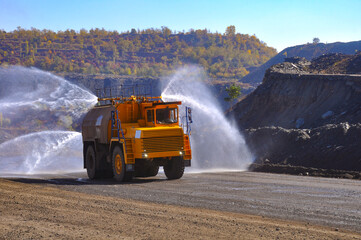 Heavy truck pours the road with water in the iron ore quarry. Dust removal, protection of the environment. Irrigation of the road from dust.