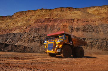 Mining dump truck transports rock, iron ore along the side of the quarry. © Yevhen
