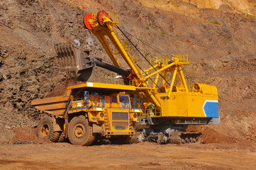 Excavator in the quarry loads the dumper with iron ore.