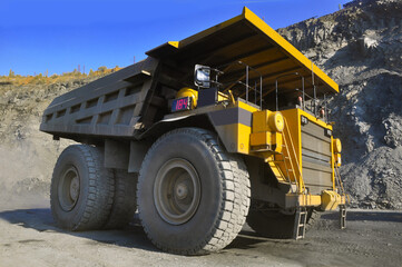  Mining dump truck transports rock, iron ore along the side of the quarry.