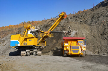 Excavator in the quarry loads the dumper with iron ore.