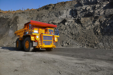 Mining dump truck transports rock, iron ore along the side of the quarry. © Yevhen
