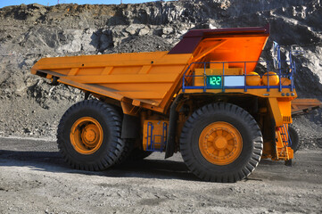 Fototapeta na wymiar Mining dump truck transports rock, iron ore along the side of the quarry.