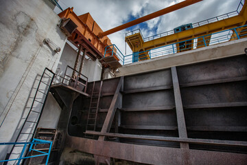 Lifting mechanism of water shutter. Shardara river dam. Grey metal shutter and yellow overhead crane. Kazaly city, Kyzylorda region, Kazakhstan.