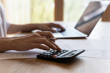Close up cropped young woman calculating household expenditures, managing monthly budget, involved...