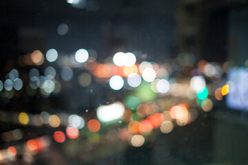 Bokeh lights on the rain look out the window .