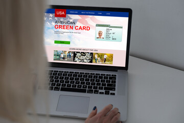 Green card in a search engine on the computer. laptop and american flag