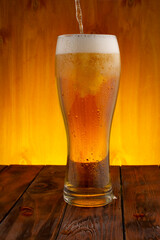 light beer is poured into a glass, wooden background