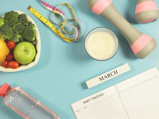 habit tracker book, wooden calendar March, gray pink dumbbells, measuring tape, water, milk  and...