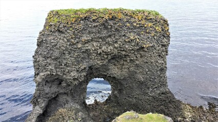 Ein schöner unterhöhlter  Basaltfelsen im Meer bei  Rauðanes , Island - Zeugnis des...