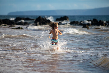 Fototapeta premium Child boy on the coast. Little kid playing in the ocean. Holidays on the sea. The child in waves.