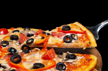 Vegetarian pizza on a kitchen spatula, isolated on black background