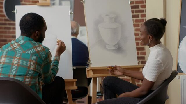 African american man and woman drawing object design with artistic tools in eduxational workshop program. Learning to draw artwork on canvas with easel for new years resolutions.