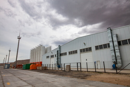 Mangystau, Kazakhstan: Bautino bay. Loading terminal on Caspian sea. Storage tanks, industrial building (warehouse). Grey storm clouds.