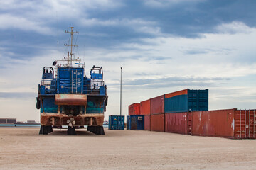 Mangystau, Kazakhstan - May 19, 2012: Bautino bay, Caspian Sea. Ship-repairing yard. Maritime (shipping) container right, ship left.  Blue sky with clouds background.